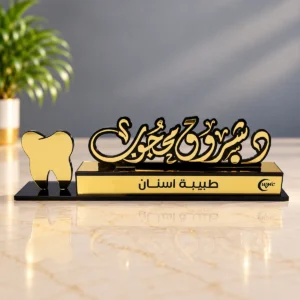 لوحة مكتبية ذهبية لطبيبة أسنان خط عربي زخرفي وقاعدة سوداء